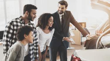 Salesperson showing a car's boot to a family of three